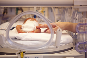 Hand touching a baby in an incubator