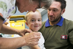 A young boy prepares to receive his immunisation from a child health nurse