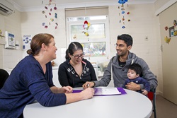 A child health nurse speaks to a mother and father, who is holding their young child