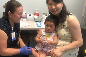 Nurse with mother and daughter performing a blood test