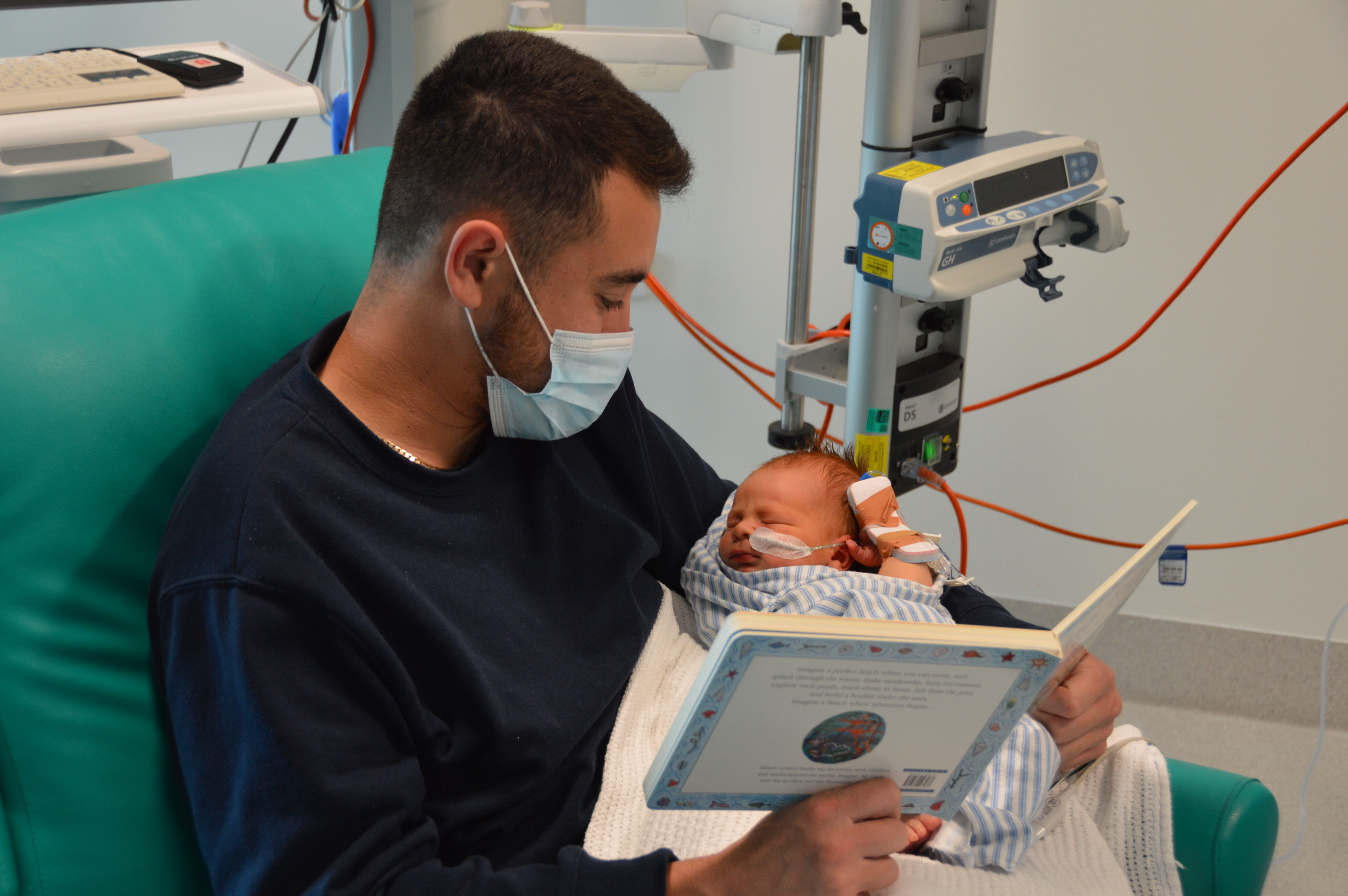 Baby Malakai being read to by dad in the NICU