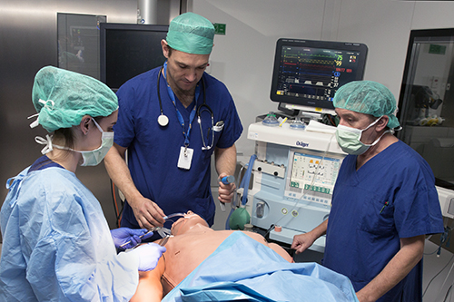 Three doctors in a theatre treating a mannequin